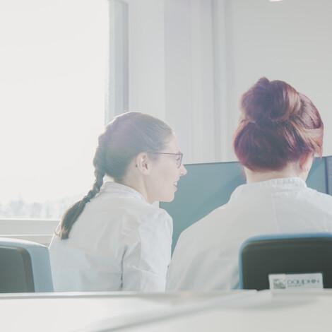 Three CUP Contract Labs employees engaged in a professional conversation in a bright office setting, symbolizing collaboration and teamwork in the field of radiopharmaceutical analytics.